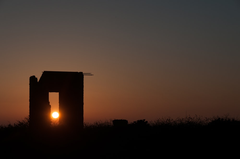 o sol está se pondo atrás de uma silhueta de um edifício