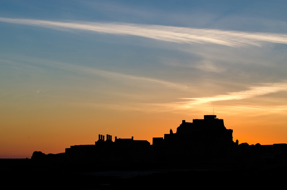 a silhouette of a building with a sky in the background