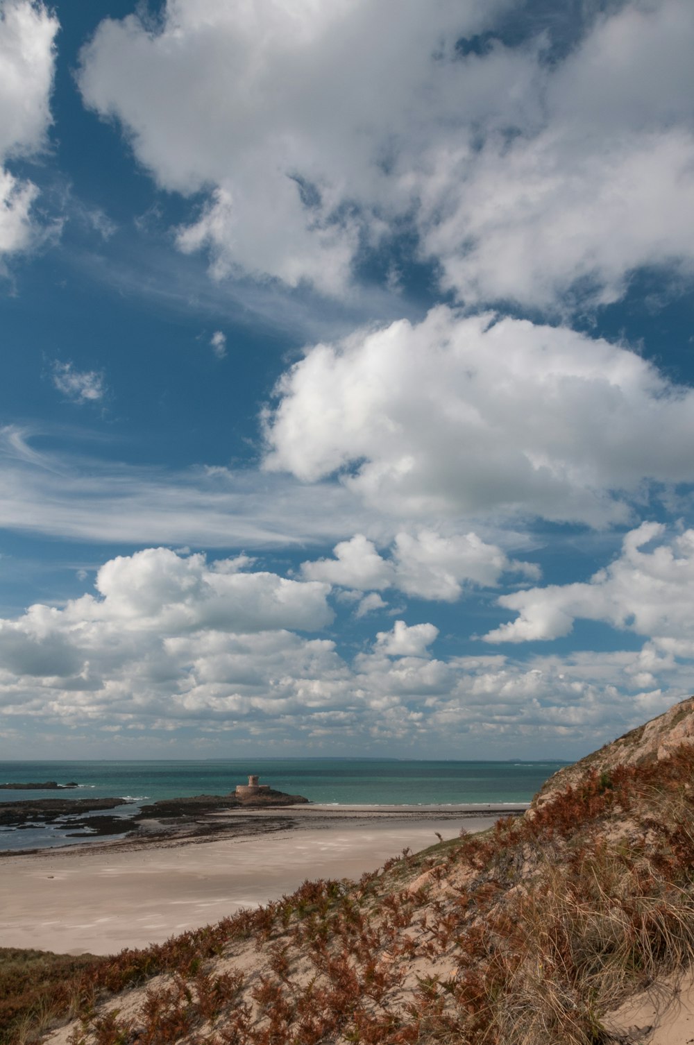 a sandy beach with a few clouds in the sky