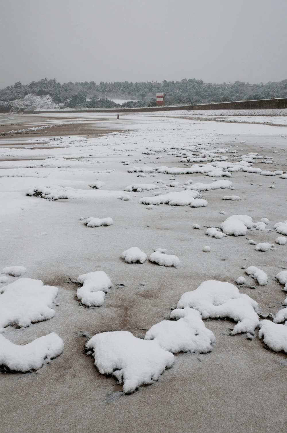 a beach covered in lots of snow next to a body of water