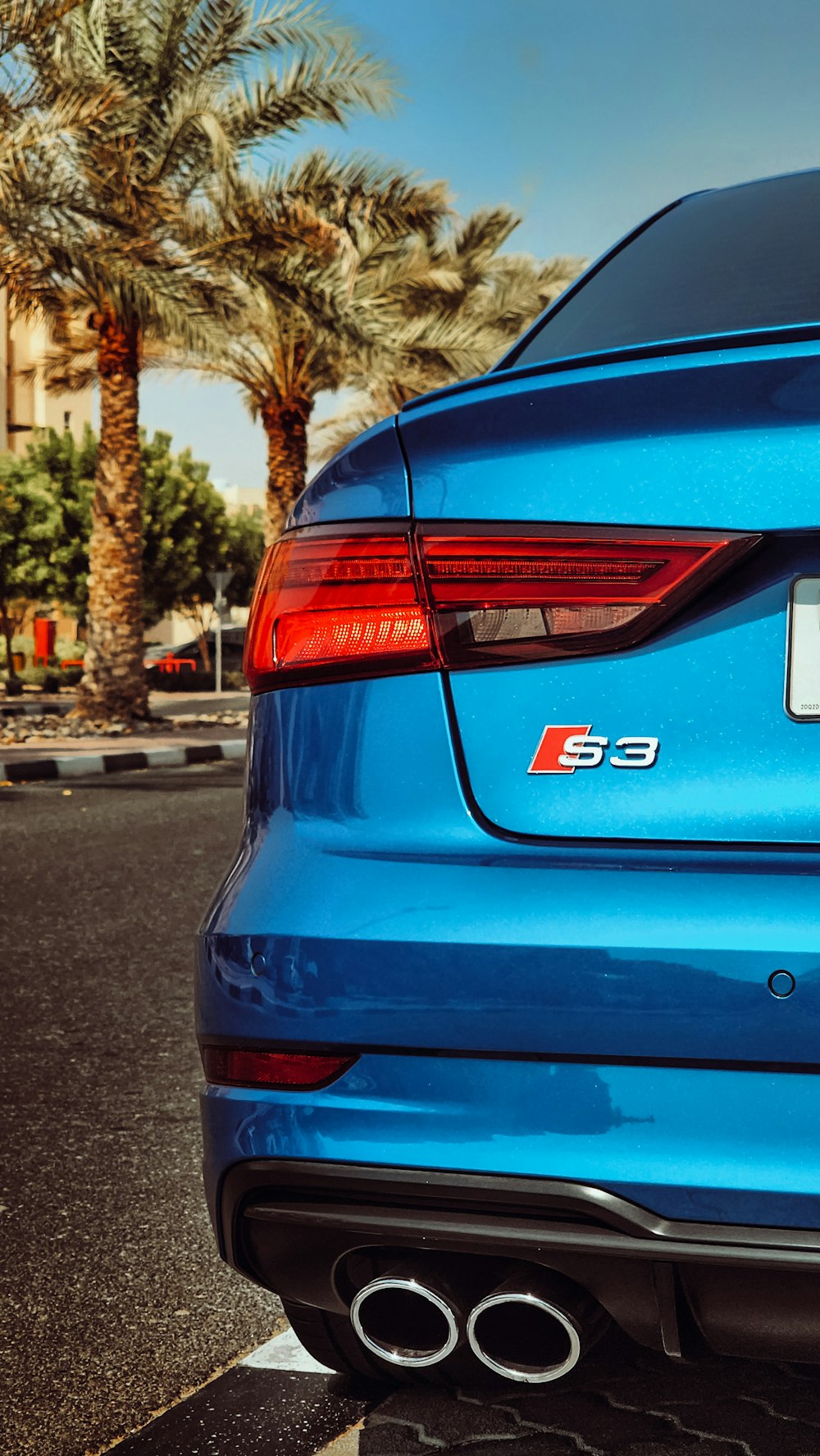 the rear end of a blue car parked in a parking lot