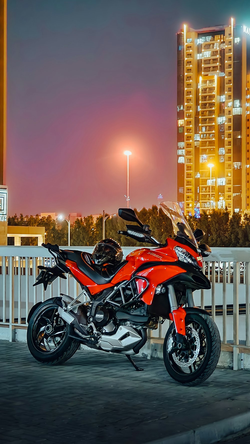 a red motorcycle parked in front of a white fence