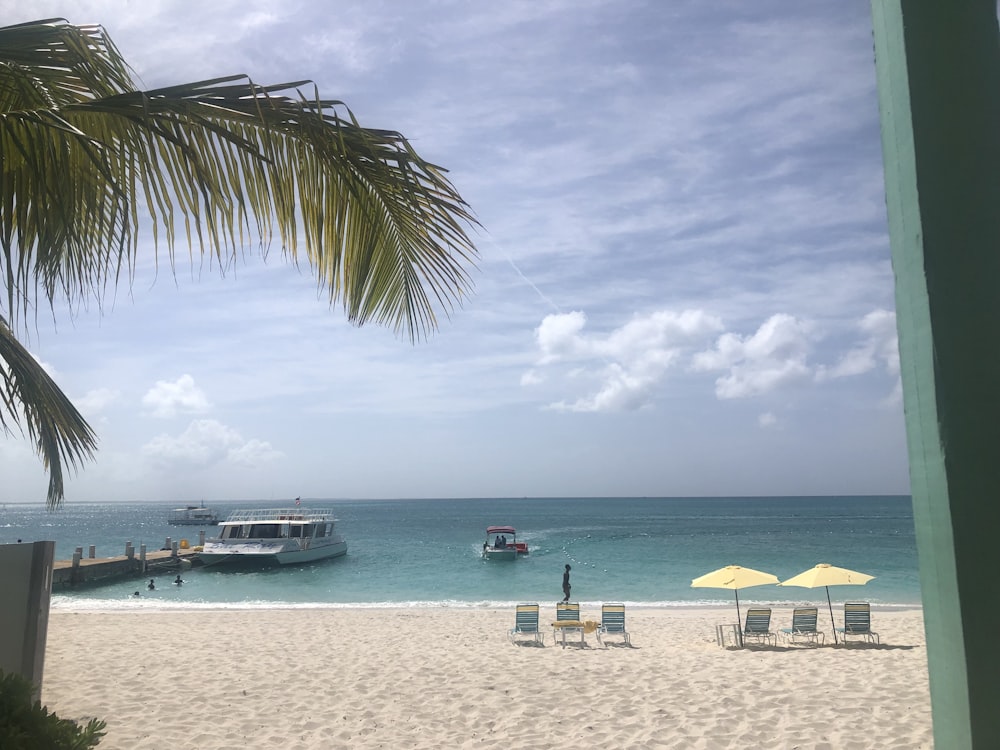 a beach with chairs and umbrellas and a boat in the water