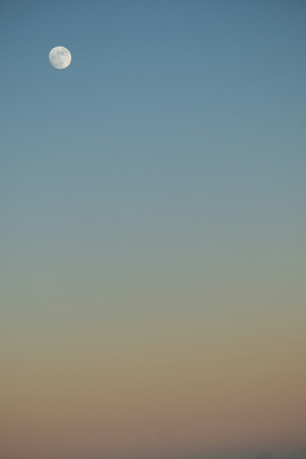 a full moon is seen in the sky above a beach