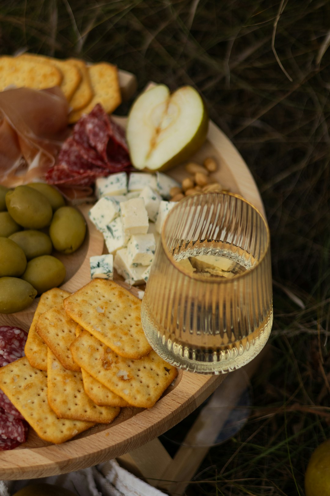 a platter of cheese, crackers, olives, and meats