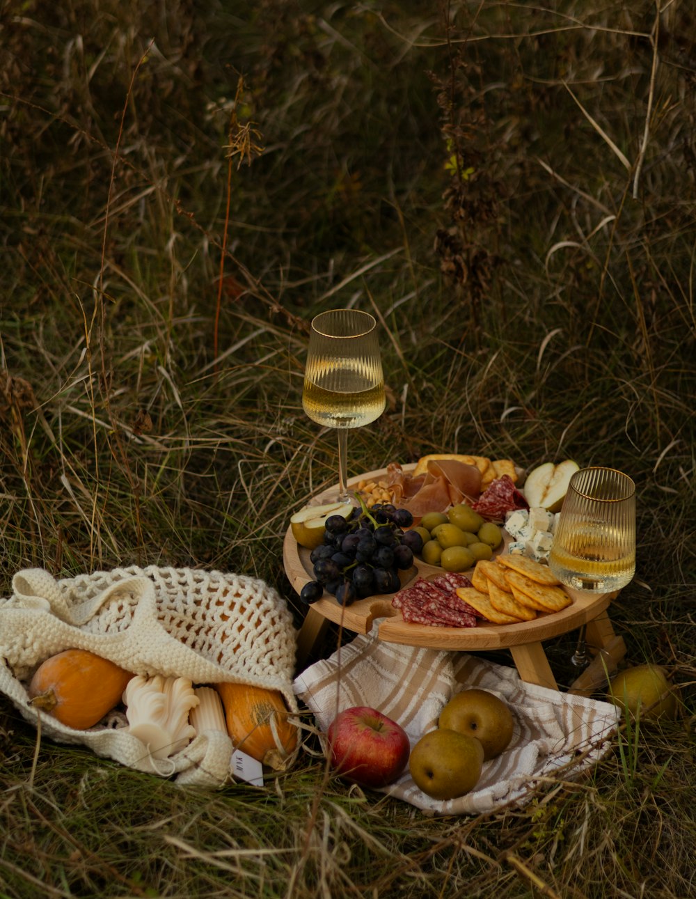 a basket of fruit and a glass of wine on the ground