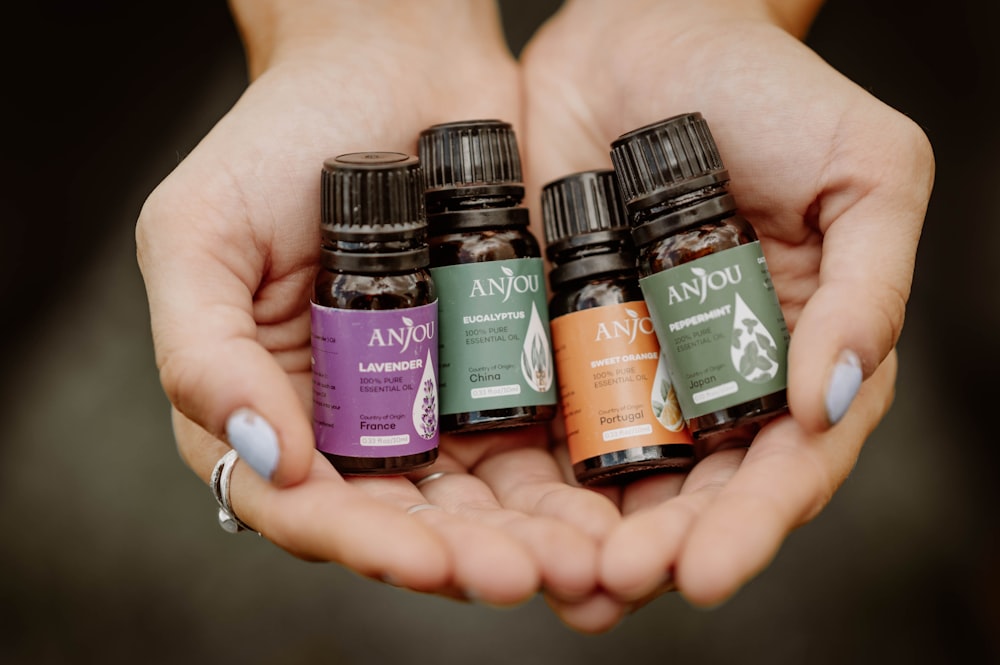 a woman holding four bottles of essential oils in her hands