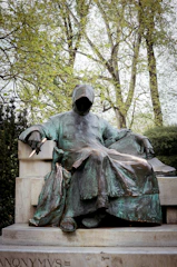 A mysterious figure cloaked in shadows holding a quill pen.