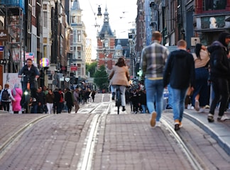a crowd of people walking down a street next to tall buildings