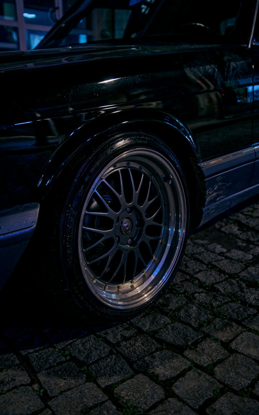 a black car parked on a cobblestone street