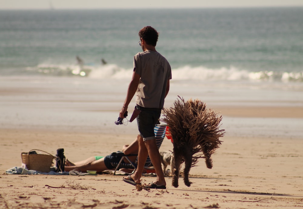 a man walking a dog on a beach next to the ocean