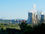 Aerial view of a large power plant surrounded by natural greenery and clean infrastructure.