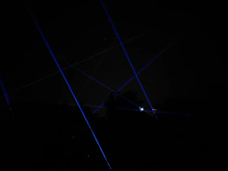 Laser rangefinder emitting a red beam across a rocky cliffside at sunset.