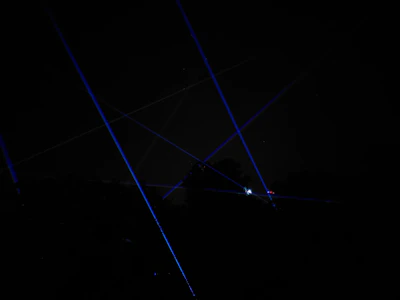 Laser rangefinder emitting a red beam across a rocky cliffside at sunset.