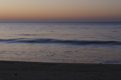 A serene beach scene during sunset with gentle waves.