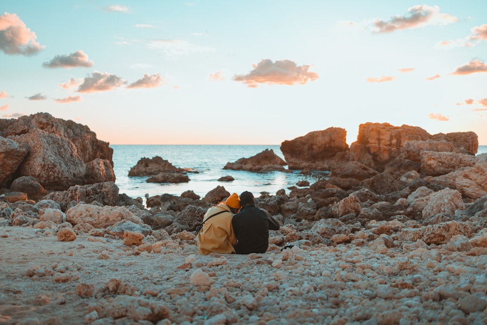 a person sitting on a rocky beach near the ocean