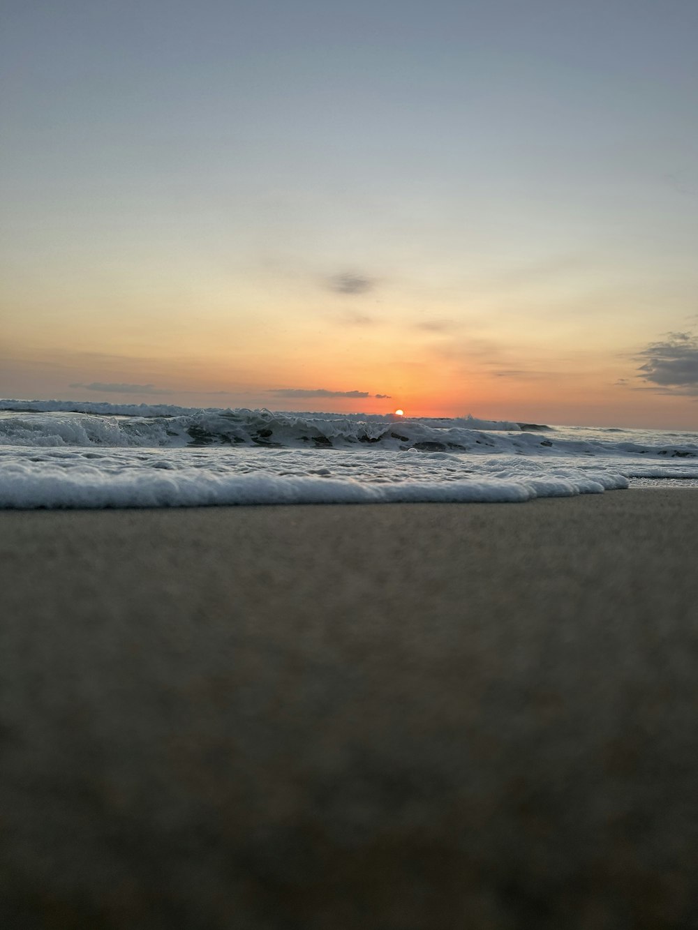 the sun is setting over the ocean on the beach