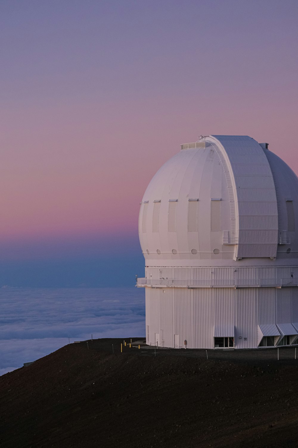 um grande telescópio branco sentado no topo de uma colina