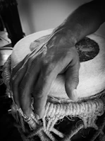 An aged, beautifully worn mandar drum resting on handmade paper with earthy red soil background