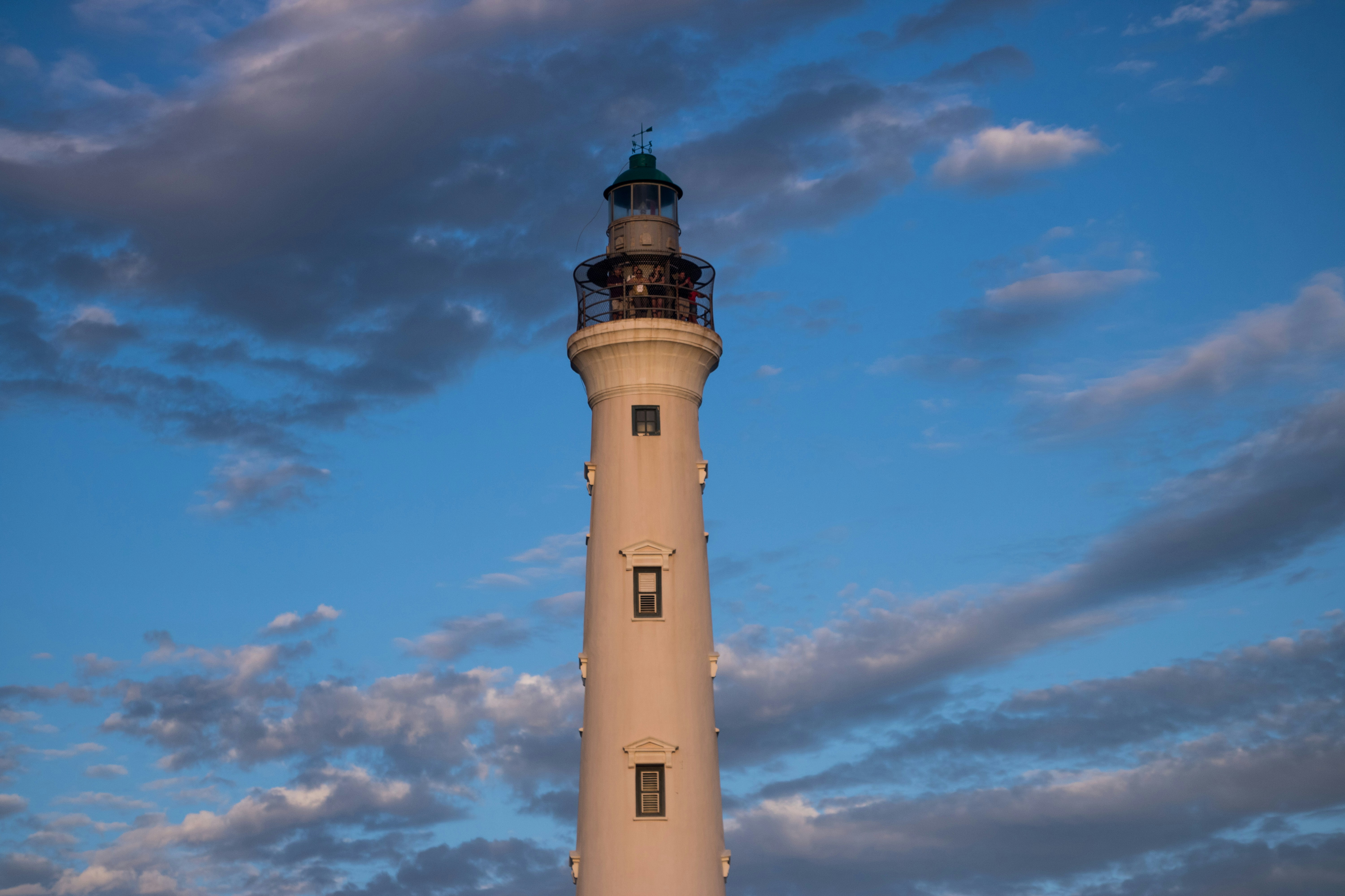 a tall light house sitting under a cloudy blue sky
