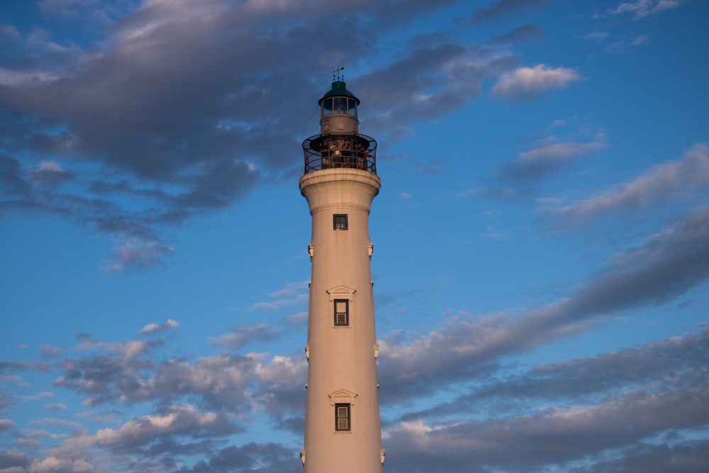 Ein hoher Leuchtturm sitzt unter einem wolkenverhangenen blauen Himmel