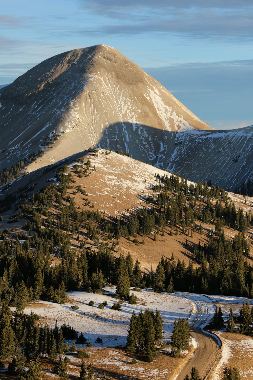 a snow covered mountain with a winding road in the foreground