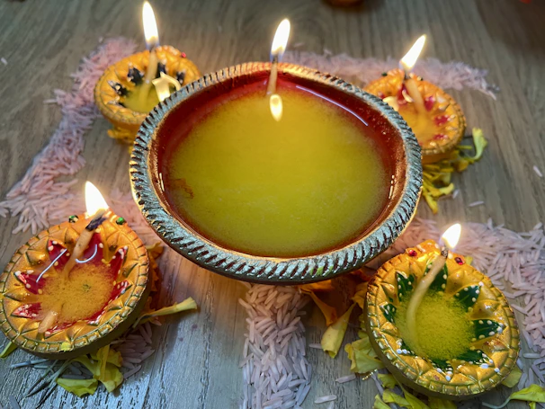 A festive arrangement of diyas placed on a rangoli pattern with flickering flames.