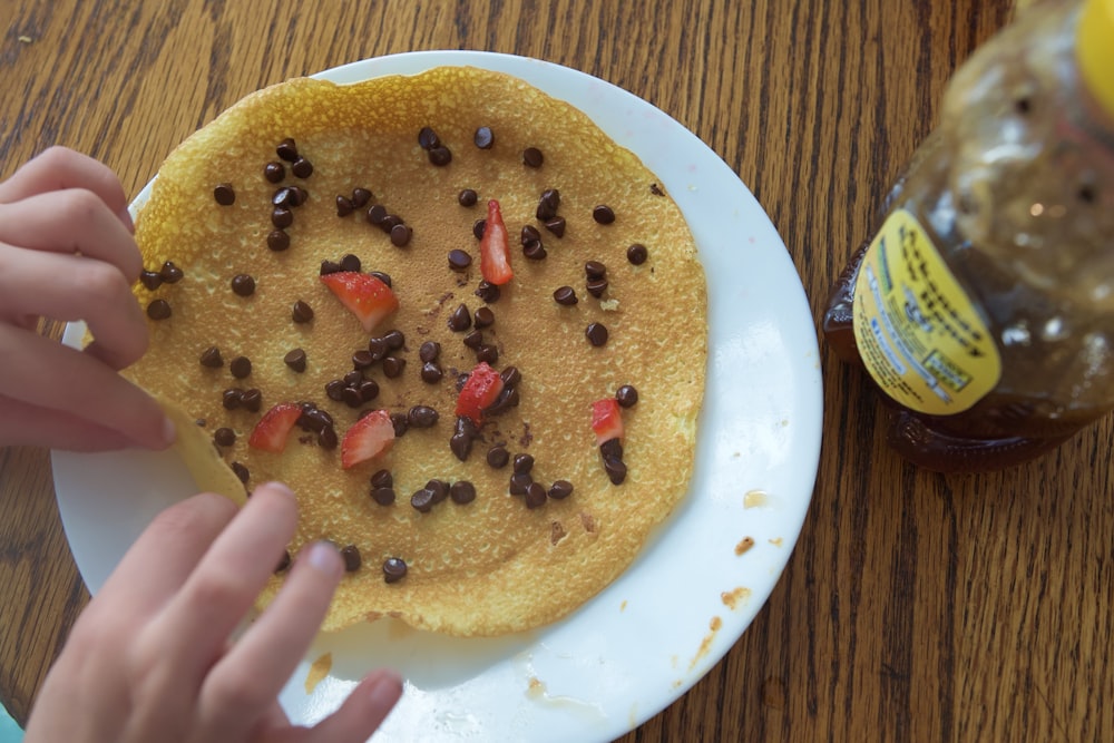 a plate of pancakes with chocolate chips and strawberries