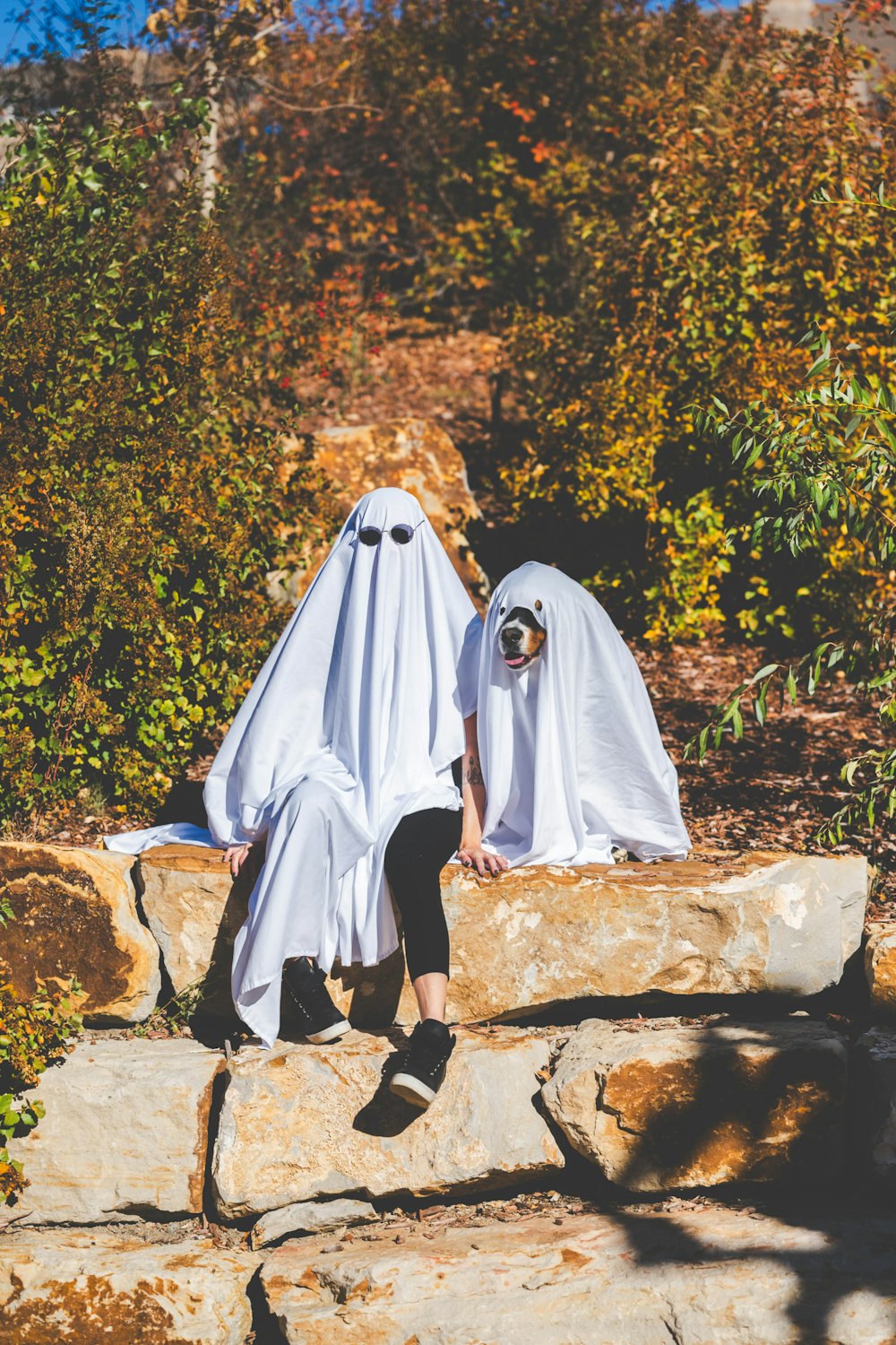 two people dressed as ghostes sitting on a rock