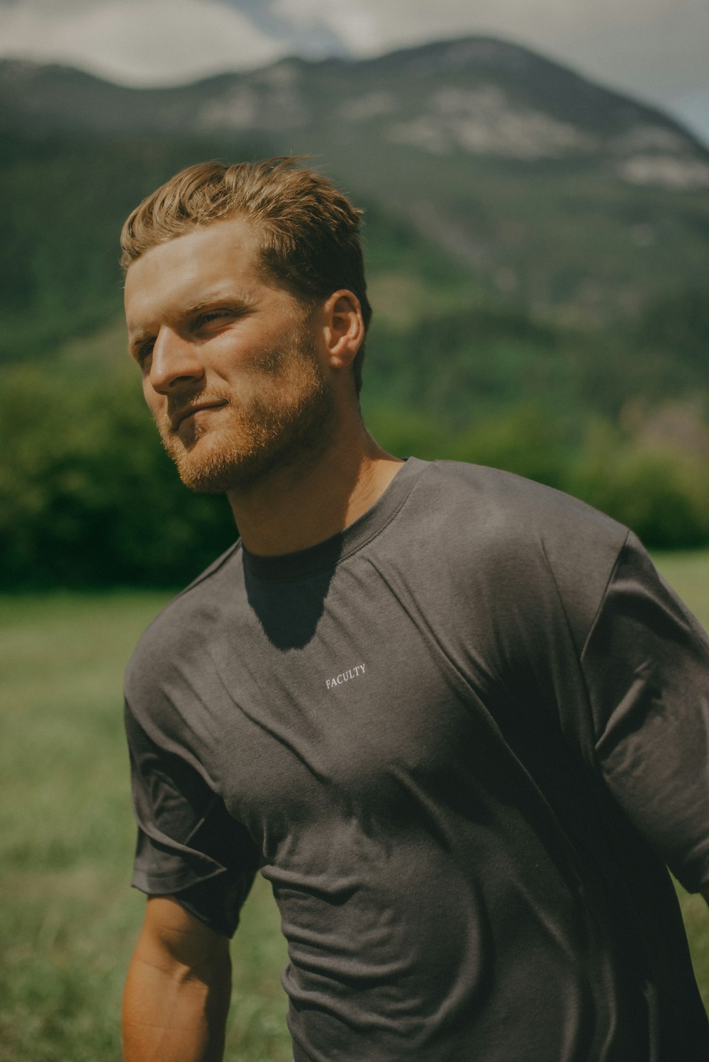 a man standing in a field with mountains in the background