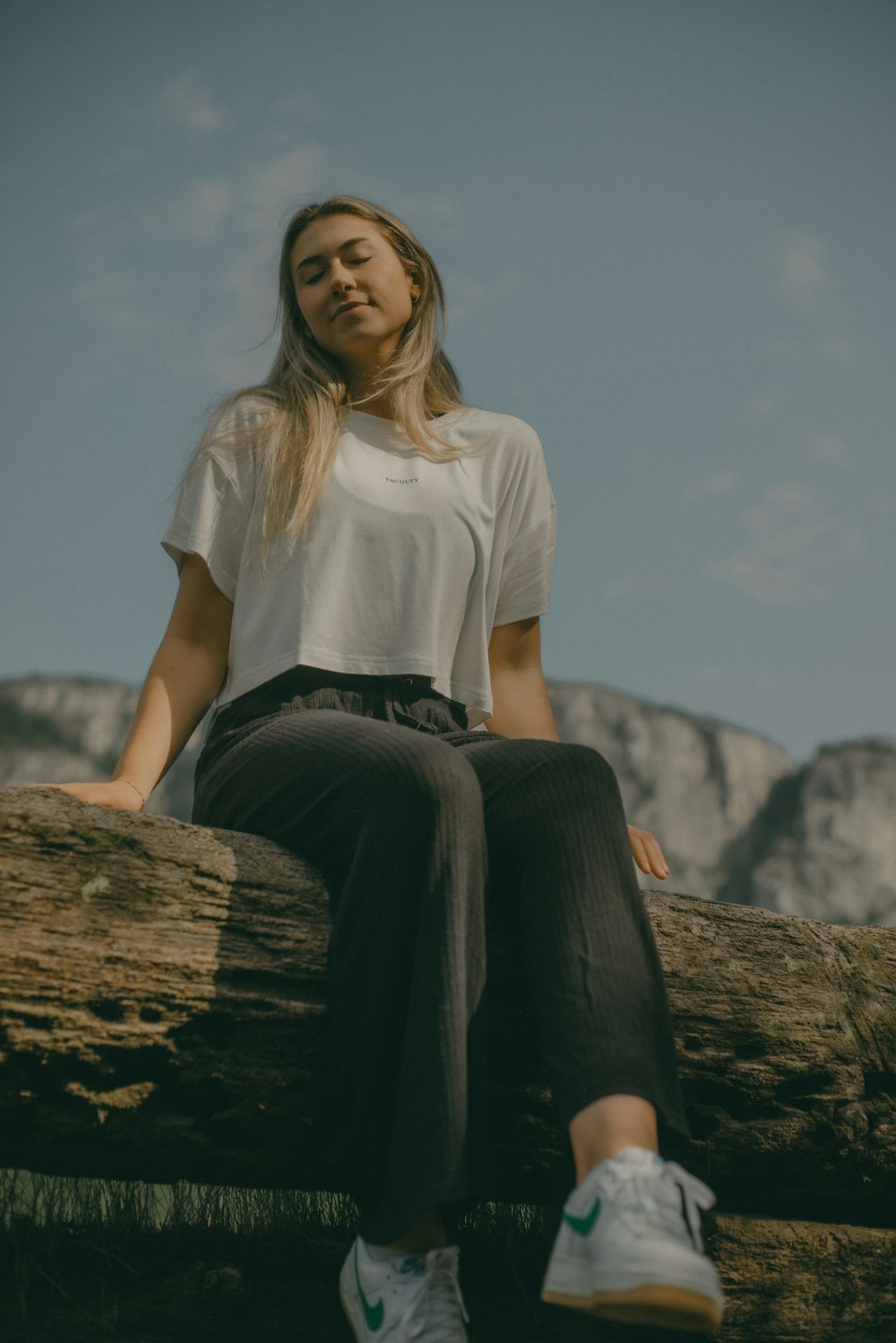 a woman sitting on top of a tree log