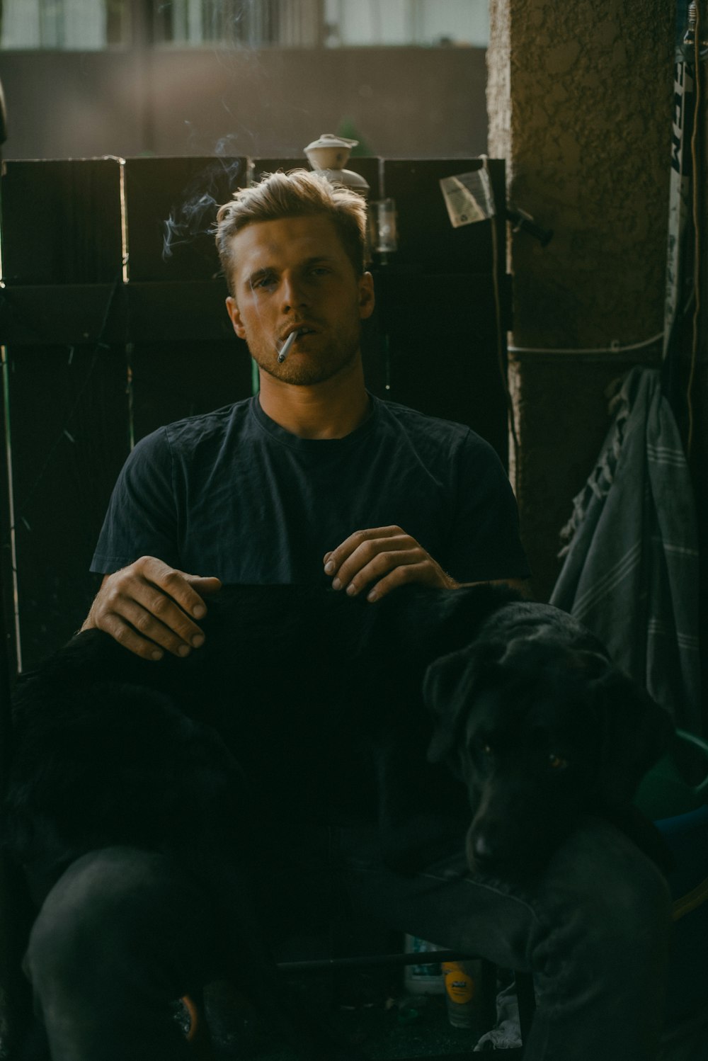 a man smoking a cigarette while sitting next to a dog