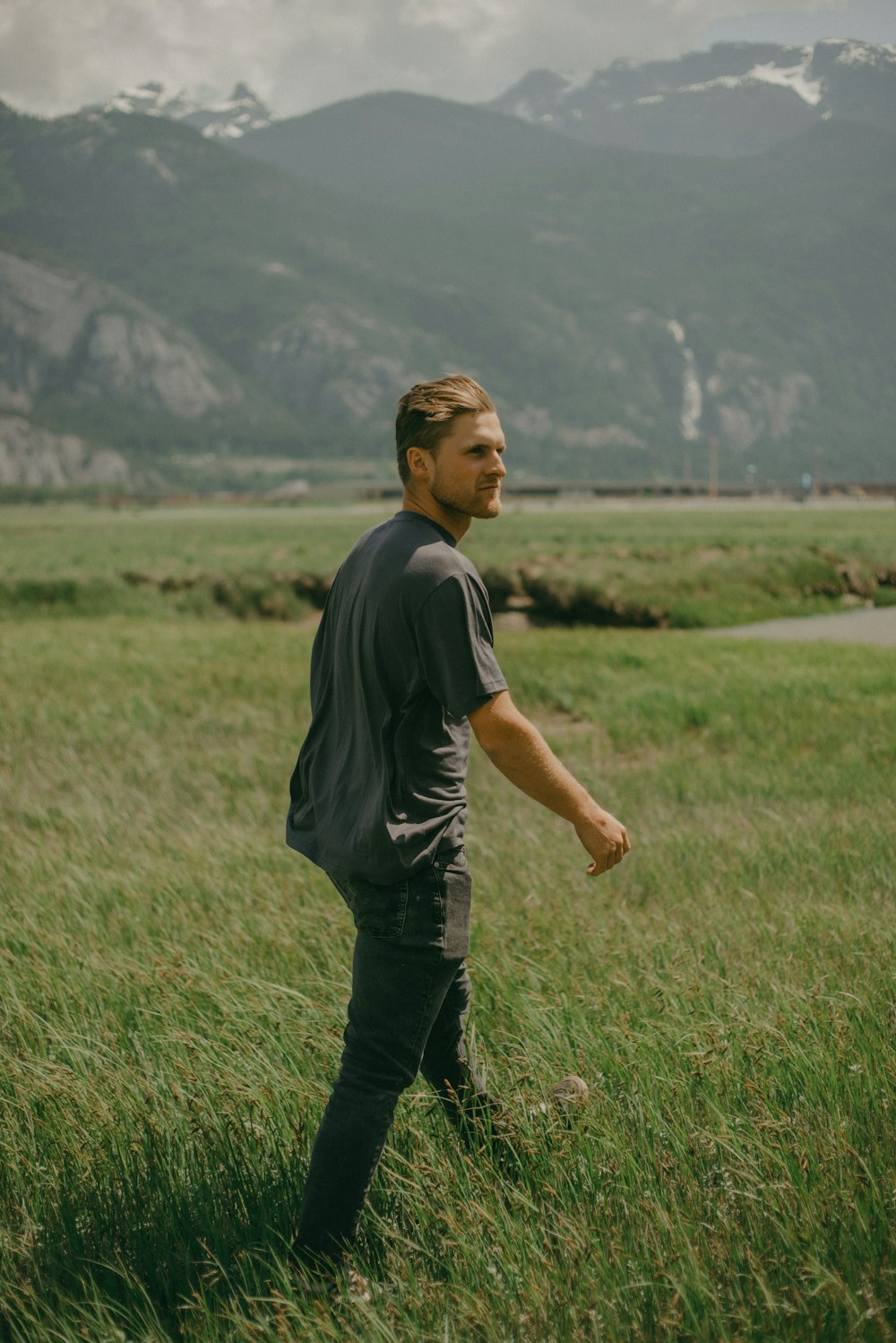 a man standing in a field with mountains in the background