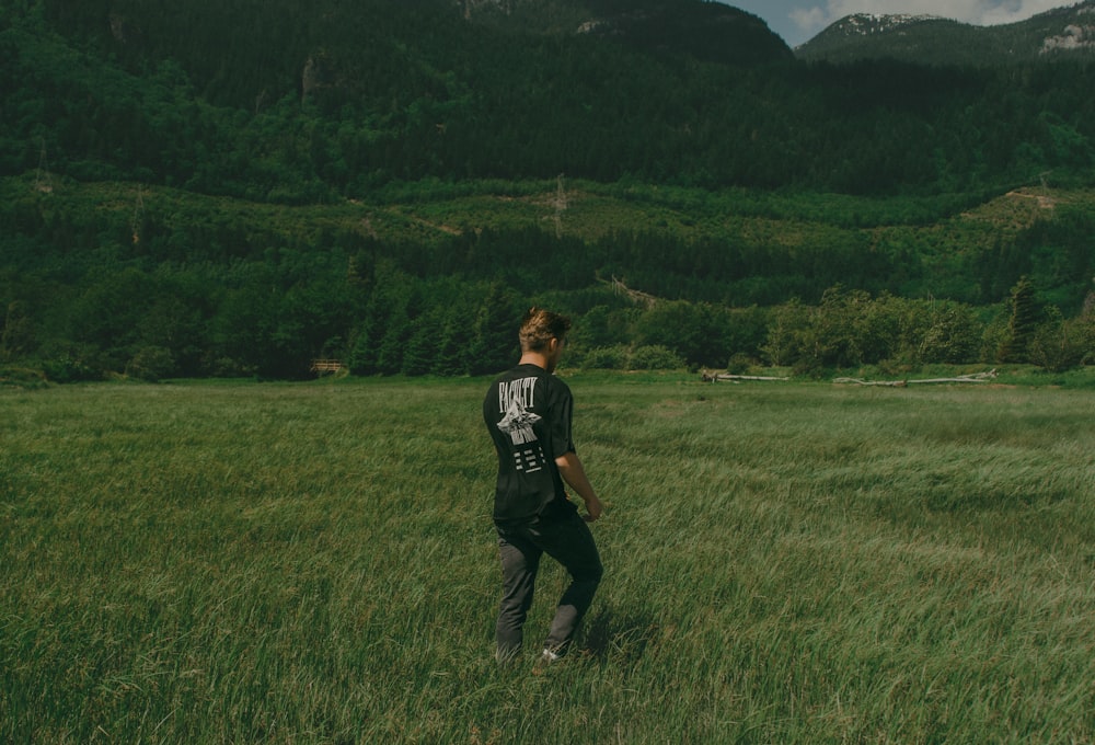 a man standing in a field with mountains in the background