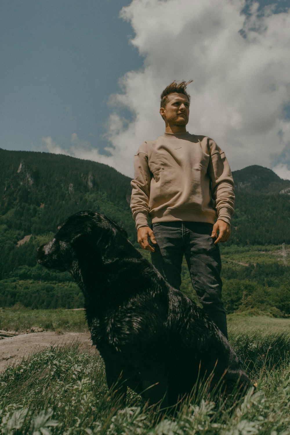 a man standing next to a black dog