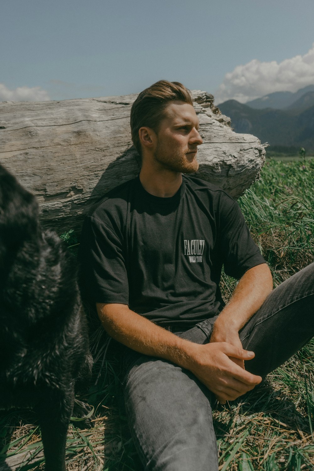 a man sitting on the ground next to a dog