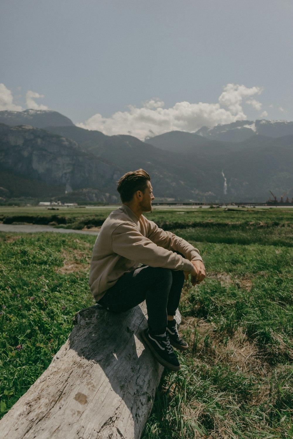 a man sitting on a log in a field