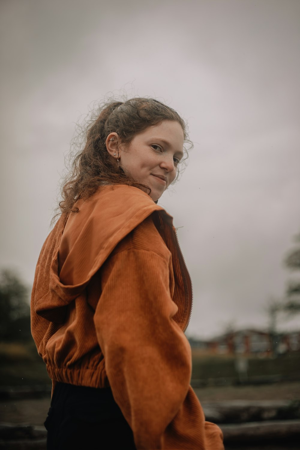 a young girl in an orange jacket smiles at the camera