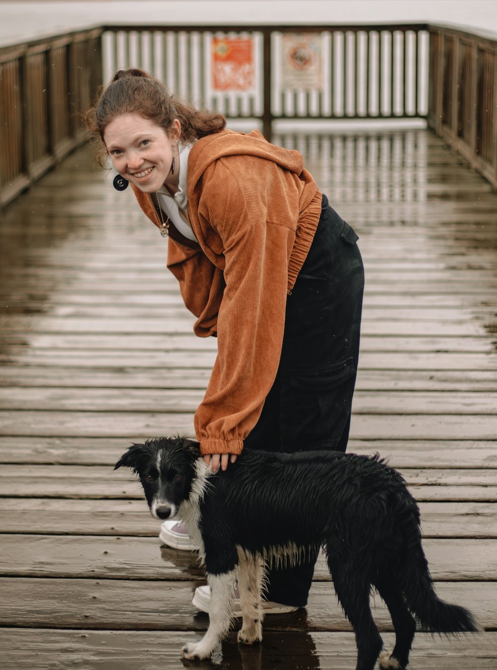 a woman standing on a bridge with a dog