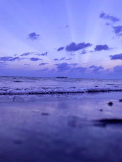 A serene oceanside view at sunset with gentle waves and soft pastel skies.