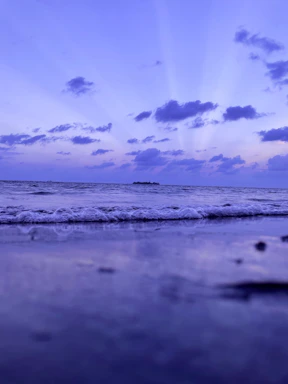 A serene oceanside view at sunset with gentle waves and soft pastel skies.