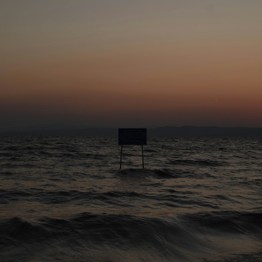 a sign sitting in the middle of a body of water