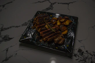 Elegant plating of grilled meats accompanied by traditional sides on a dark slate.