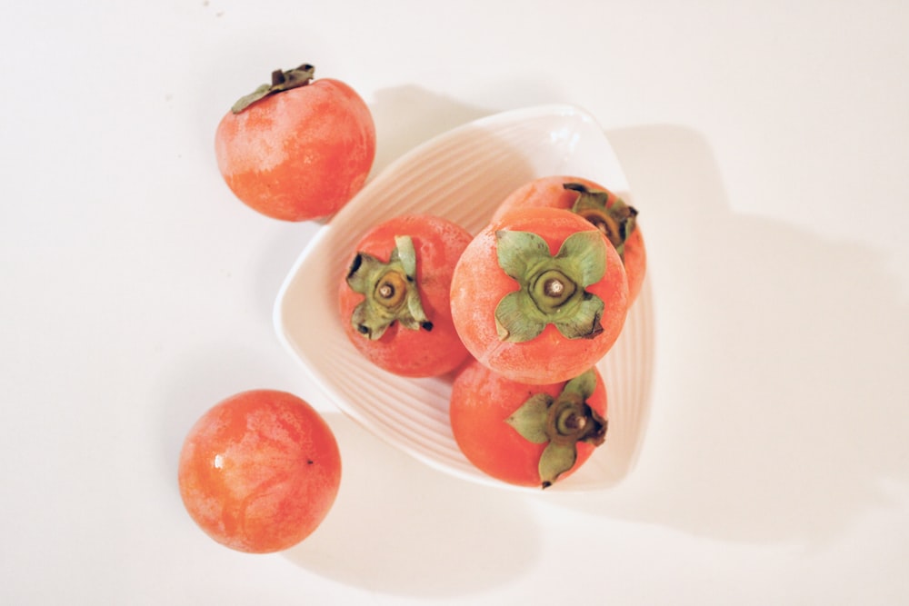 a white bowl filled with tomatoes on top of a table