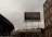 A large outdoor billboard advertises the iPhone 15 Pro with the word 'Titanium' prominently displayed. The billboard is situated in an urban setting, surrounded by buildings and a highway overpass. The sky is overcast, giving a muted feel to the scene.