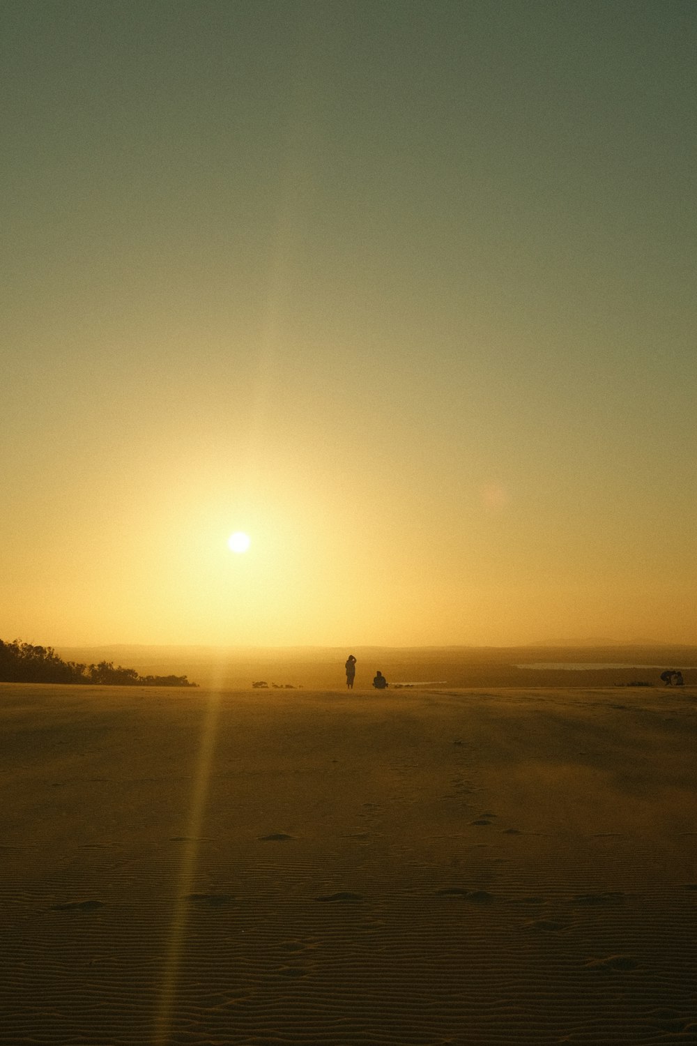 the sun is setting over a sandy area