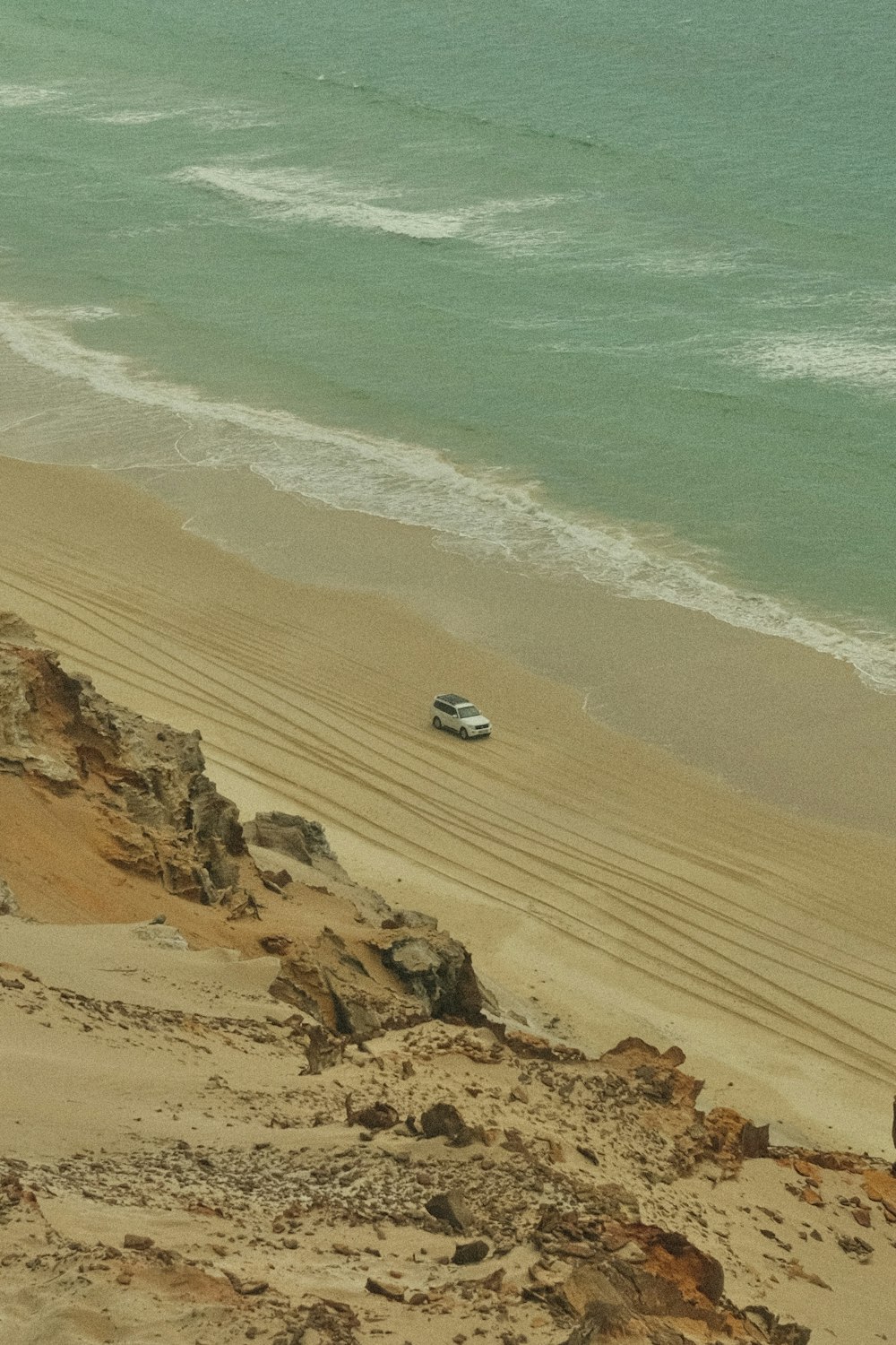 a car is parked on the beach near the water