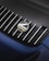 A close-up of a car's rear grille featuring the Porsche logo with the word 'heritage' written beneath it. The grille is composed of black vertical slats with silver accents.