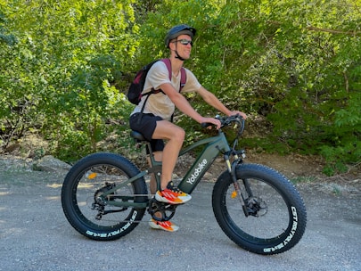 A happy customer riding an electric off-road bike on a forest trail.