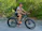 Smiling man wearing a helmet on a Voltridge electric dirt bike in a forest trail